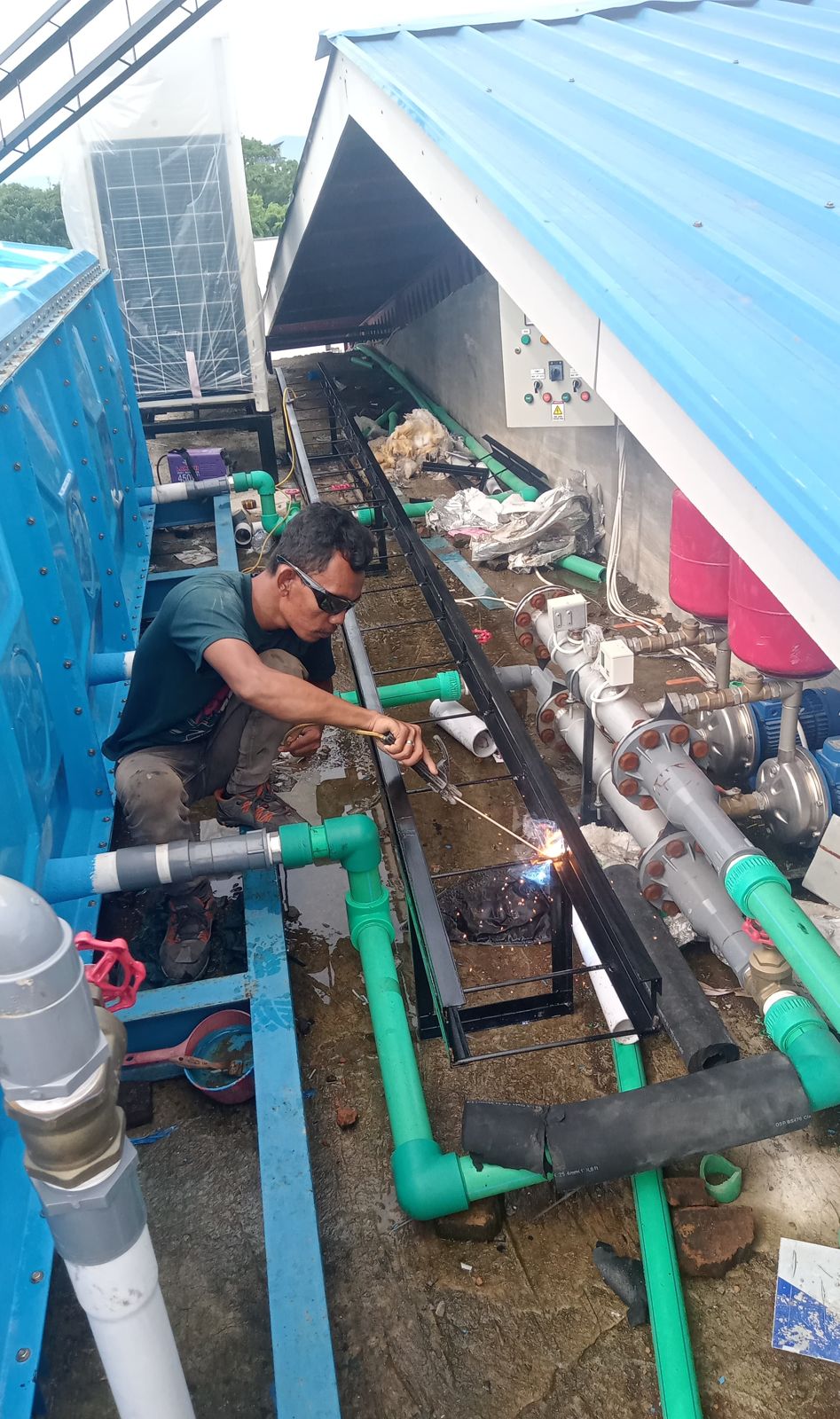 Teknisi merapikan jalur pipa refrigerant dan drainase di atap