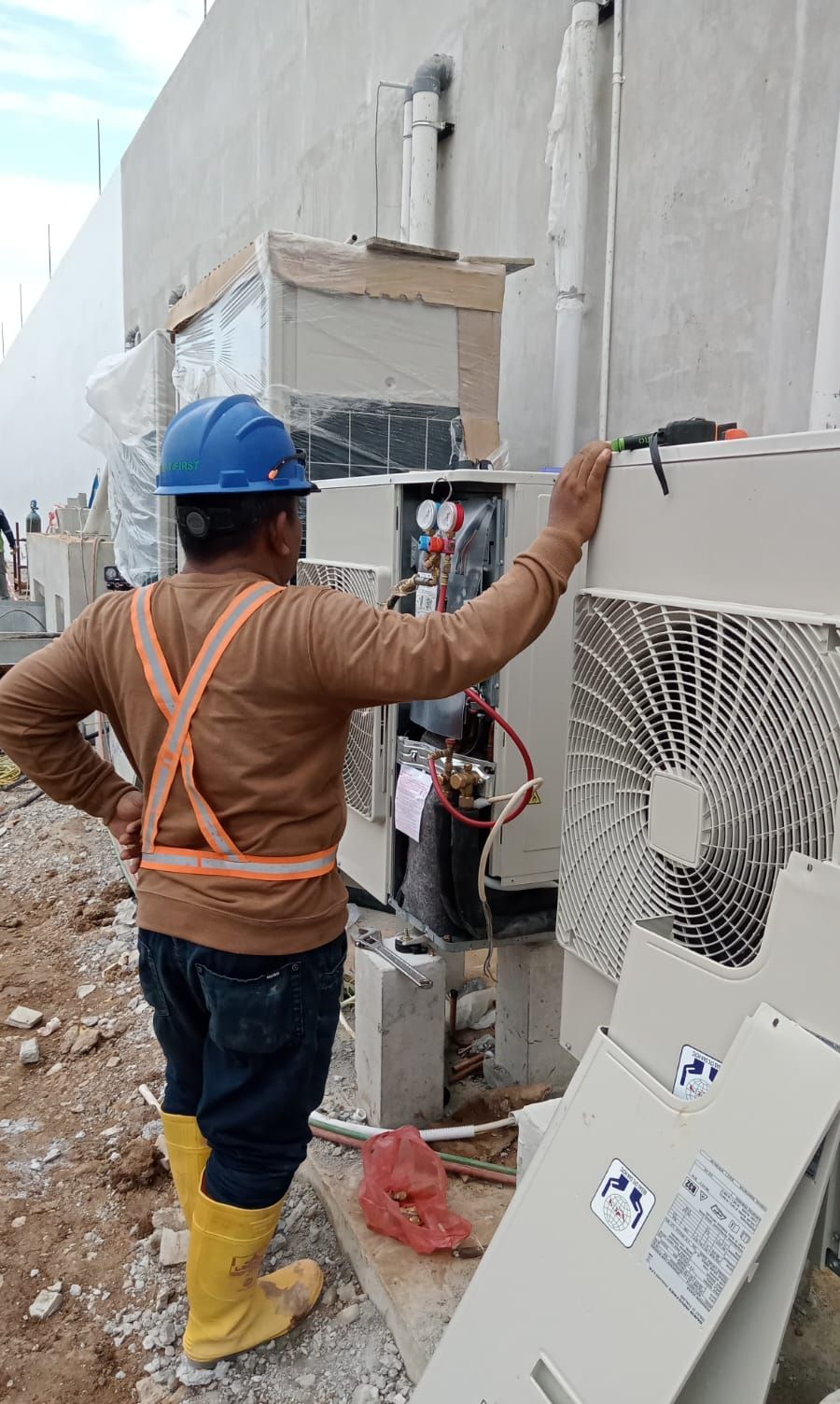 Teknisi memasang outdoor unit di sisi bangunan