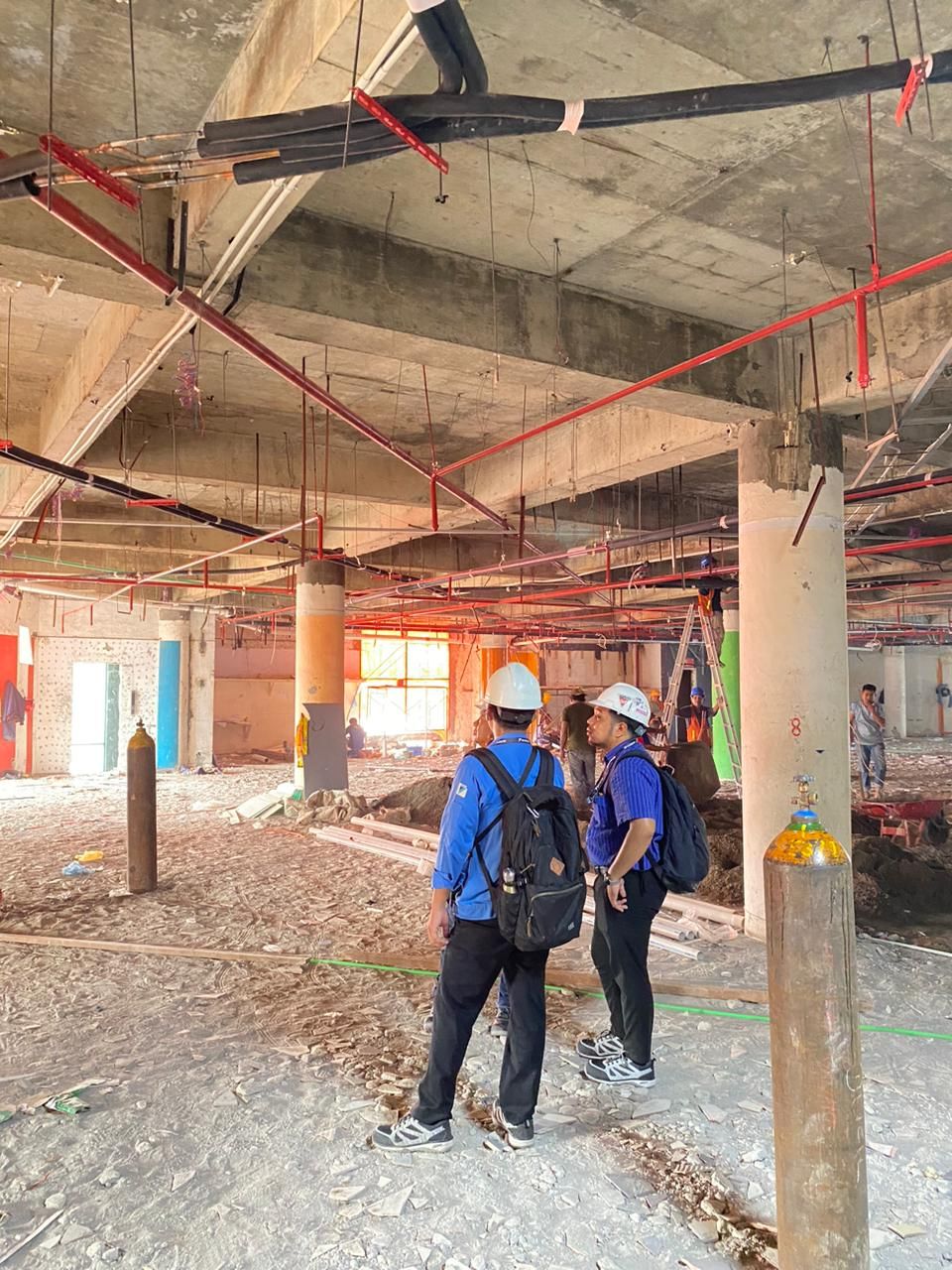 Tim survei meninjau lokasi proyek di gedung dalam tahap konstruksi
